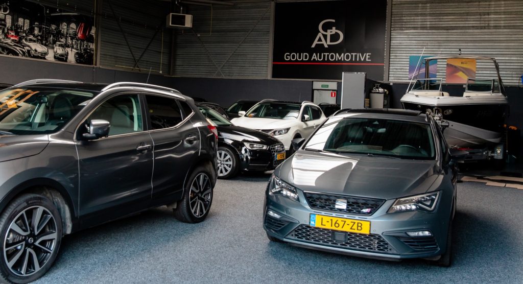 Auto's in de showroom van Goud Automotive, met het wandbord op de achtergrond