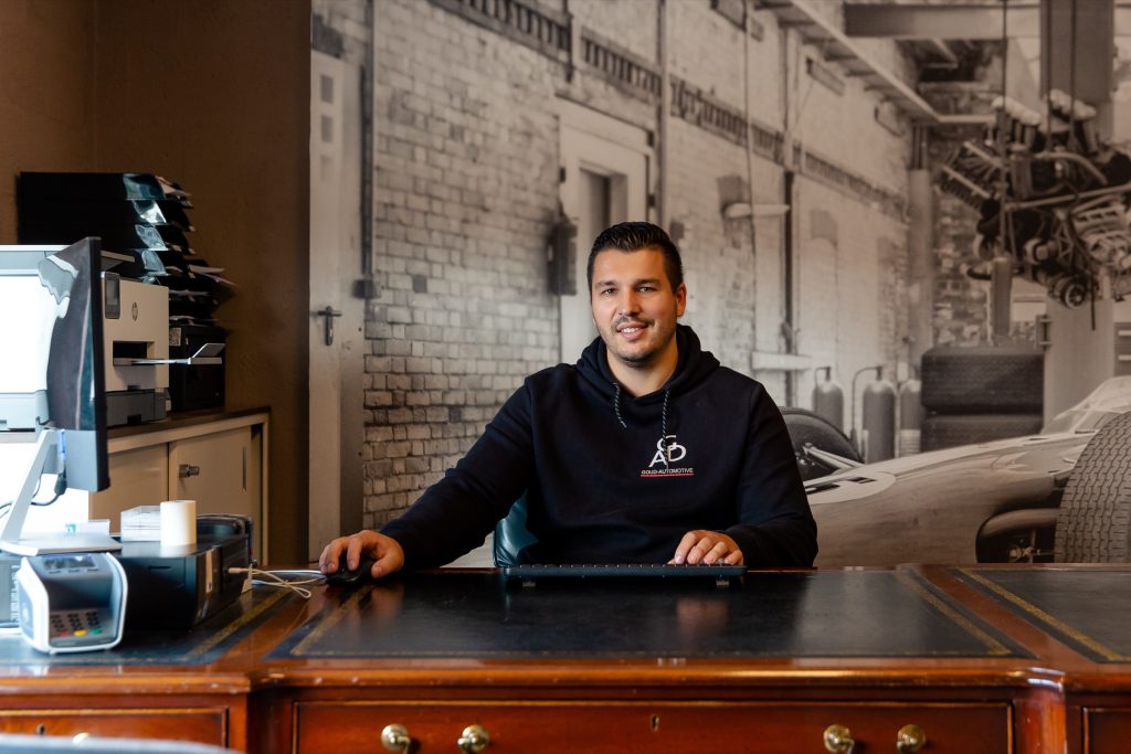 Een medewerker in een Goud Automotive-trui aan het bureau in de showroom